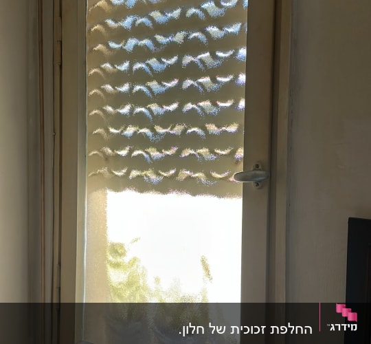 חלון עם זכוכית טקסטורלית ומחוספסת במסגרת עץ